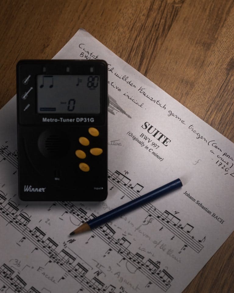 Pencil and a Digital Metro Tuner on Music Sheet